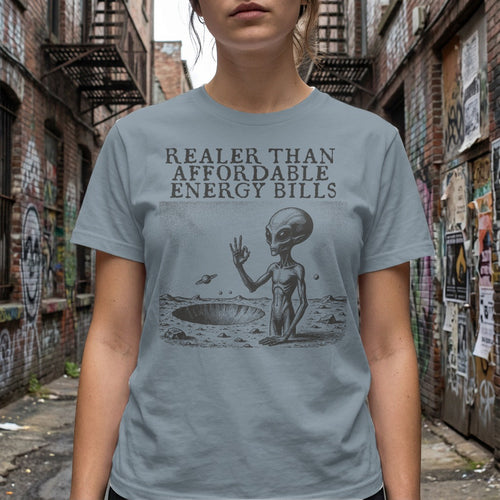 Grey t-shirt with alien in crater and text "Realer Than Affordable Energy Bills".