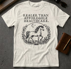 White t-shirt with a unicorn and "Realer Than Affordable Healthcare" text.