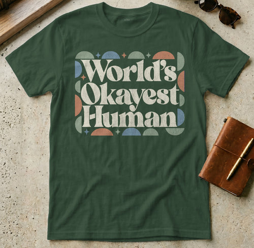 Green t-shirt with "World's Okayest Human" text and abstract geometric pattern.