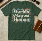 Green t-shirt with "World's Okayest Human" text and abstract geometric pattern.