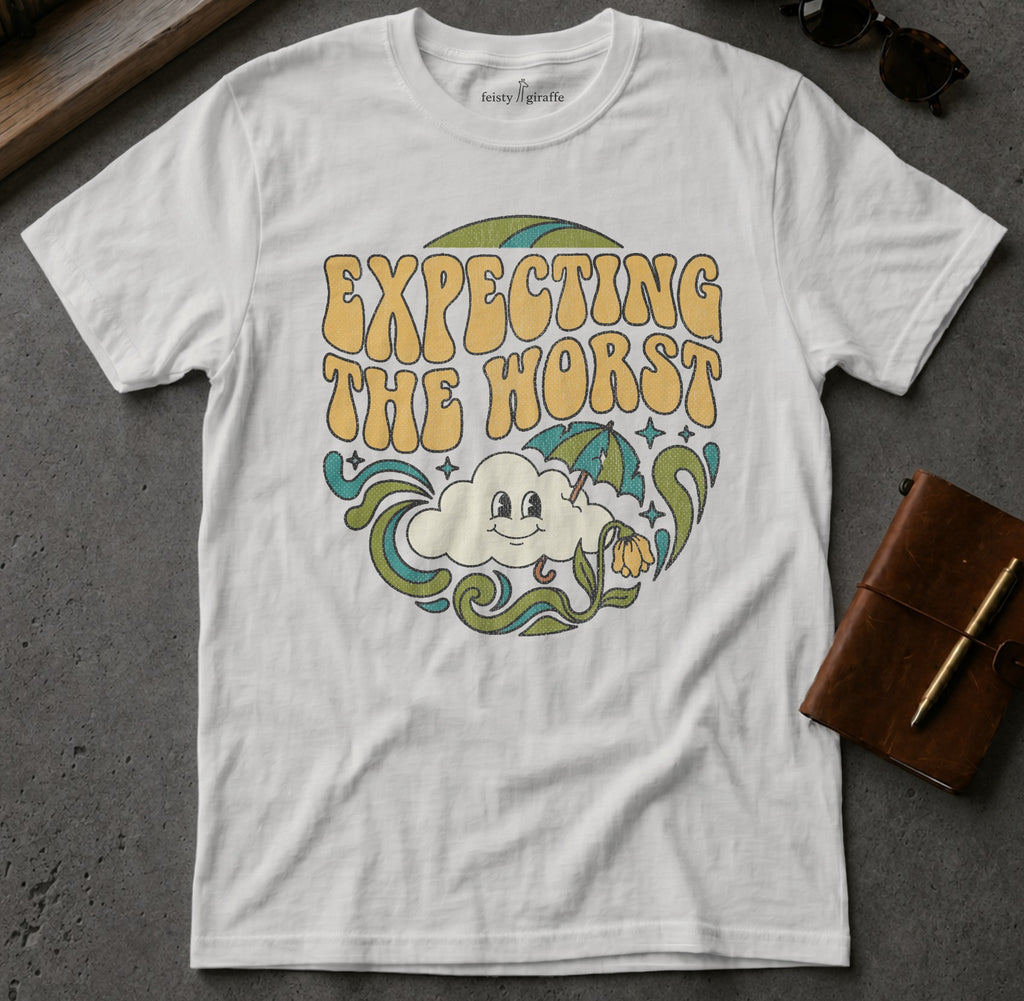 White t-shirt with retro graphic that reads "Expecting the worst" with a smiling cloud and umbrella.