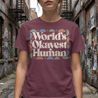 Burgundy t-shirt with "World's Okayest Human" text in retro style.