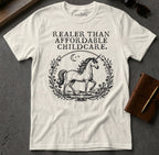 White t-shirt with a unicorn and floral wreath, "Realer than affordable healthcare" text.