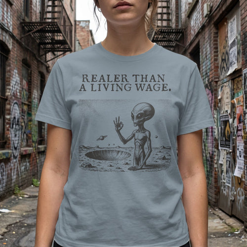 Alien on moon surface with UFO and text "Realer Than a Living Wage"